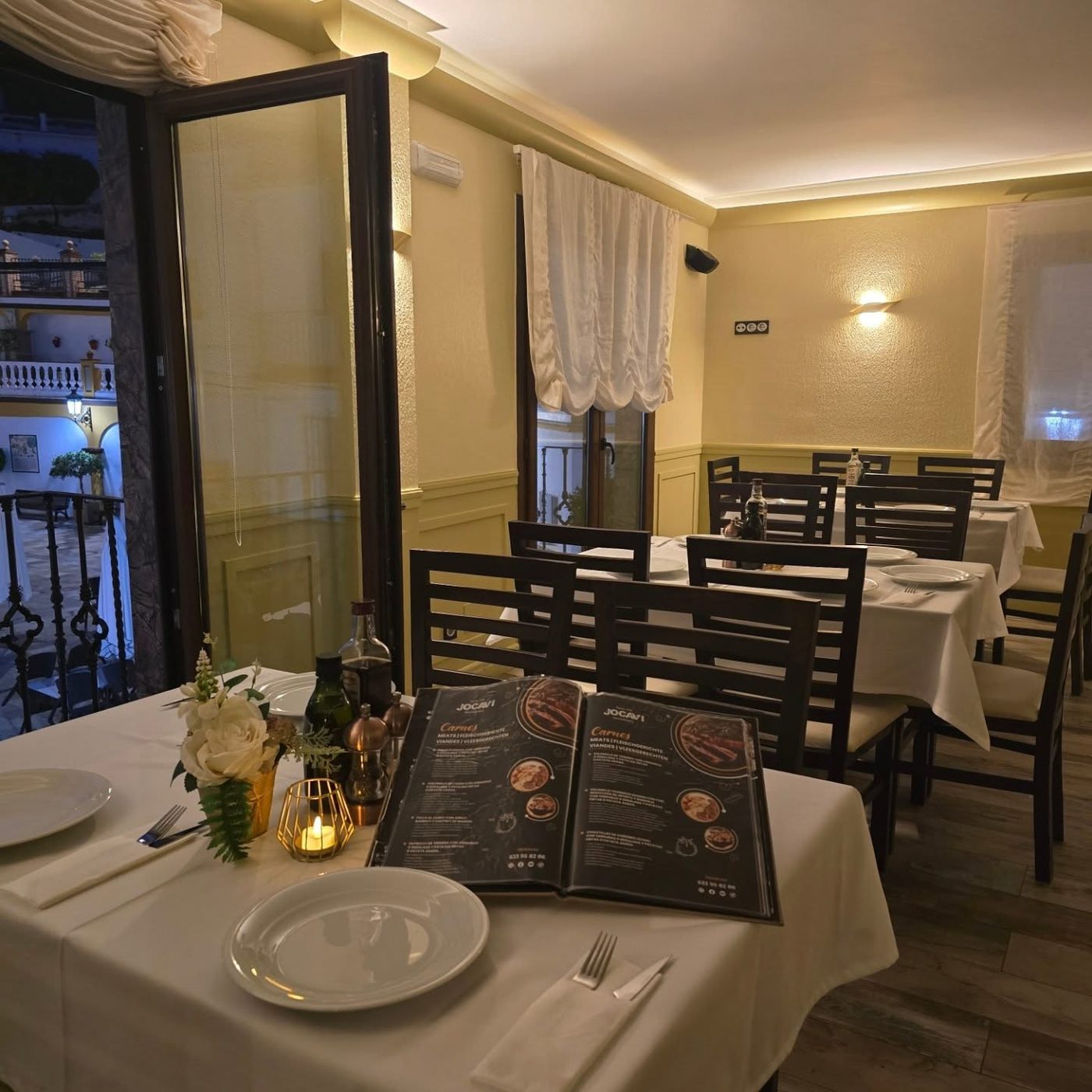Jocavi's indoor dining room with white linen and windows onto the square